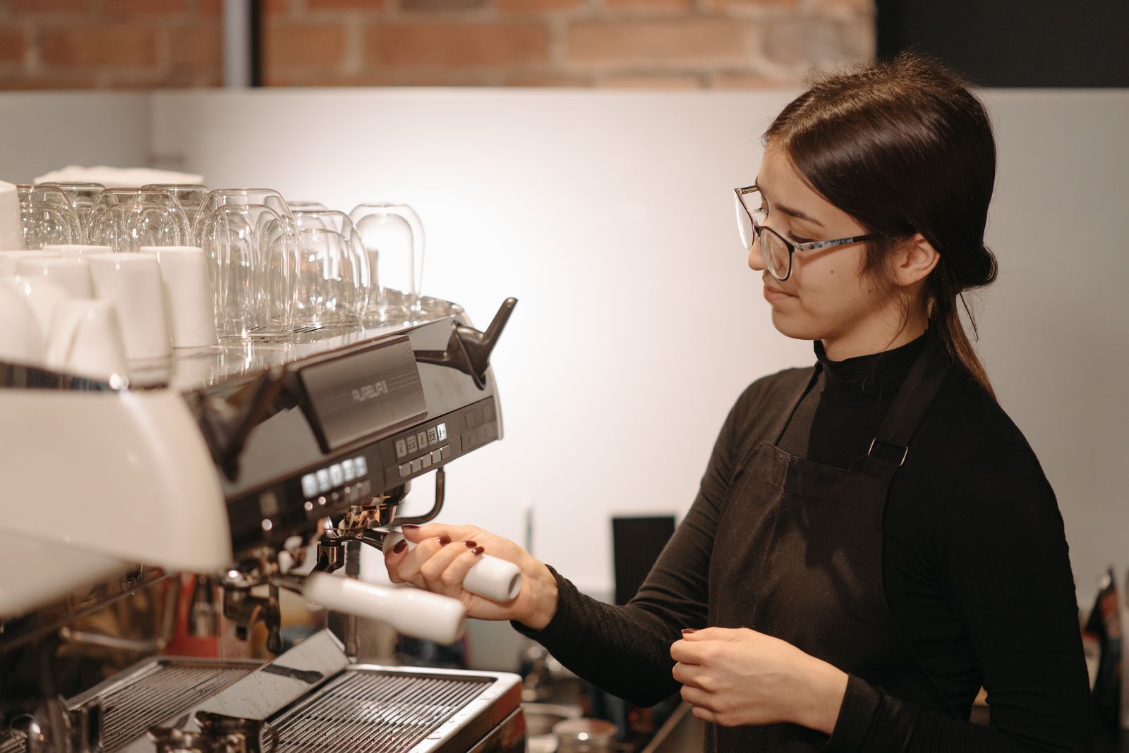 a barista steaming milk at the espresso machine